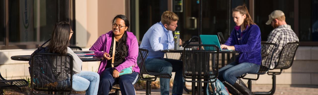 students working and talking at tables outside